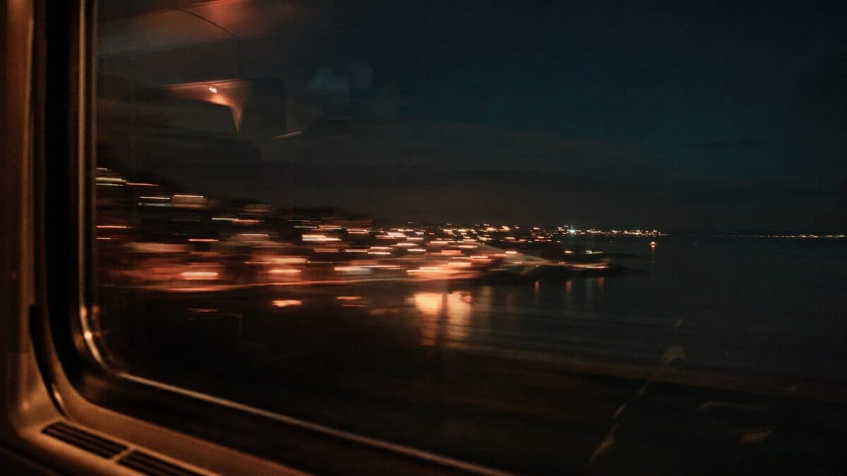 Coastal town lights streaking past a night-train window